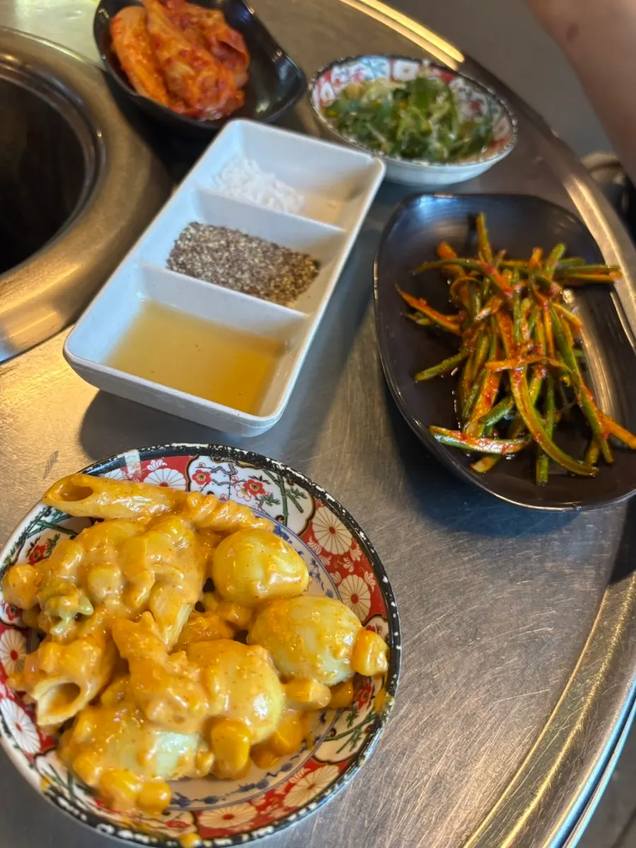 Table setting with scallion-pepper pickle, garlic scape side dish, and other banchan
