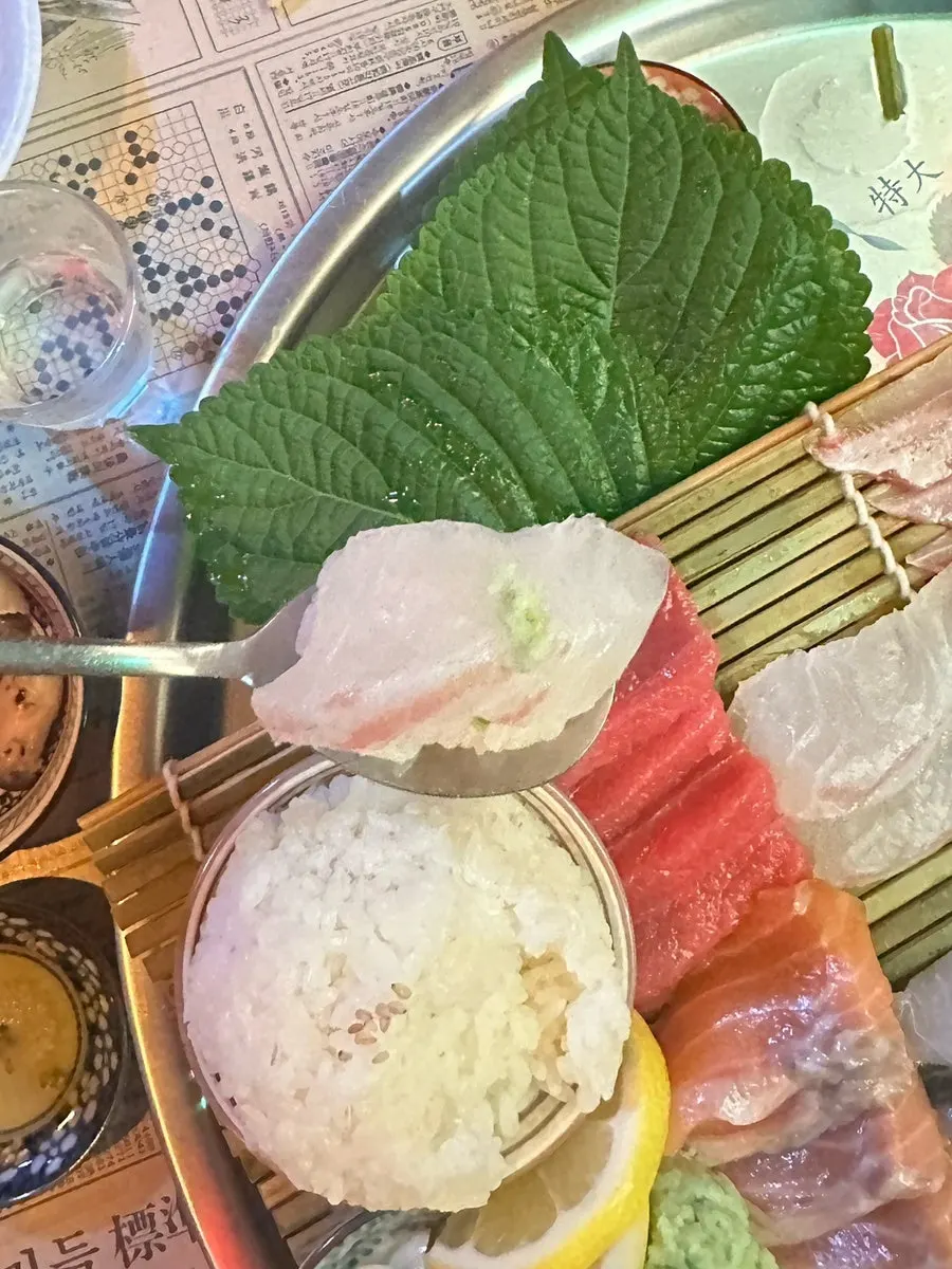 A piece of aged salmon sashimi picked up with chopsticks