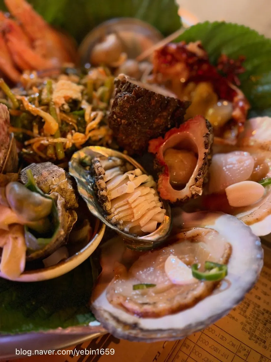 A large plate with scallops, abalone, shrimp, and shellfish