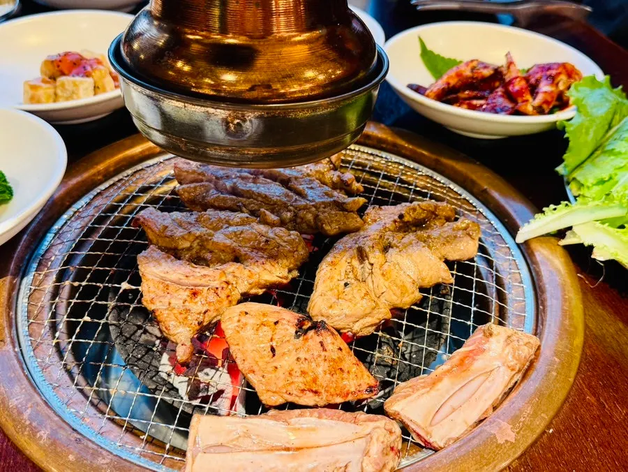 직원이 불판에서 양념 돼지갈비목살을 굽는 모습