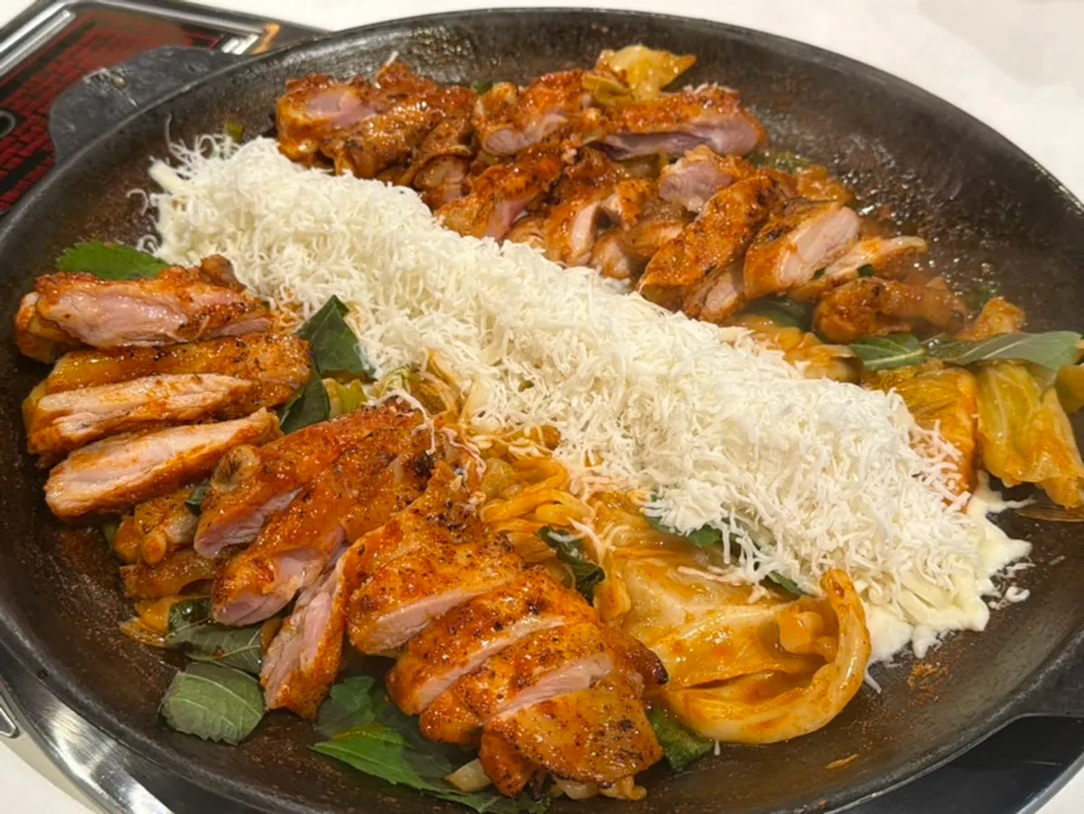 Spicy dakgalbi with cheese being pulled and stretched