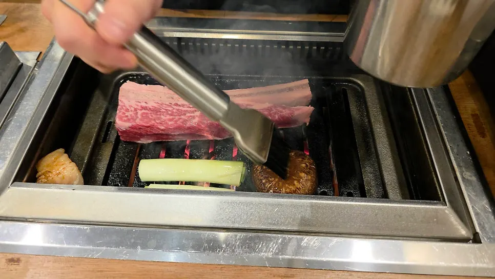 Staff grilling meat tableside on the grill plate