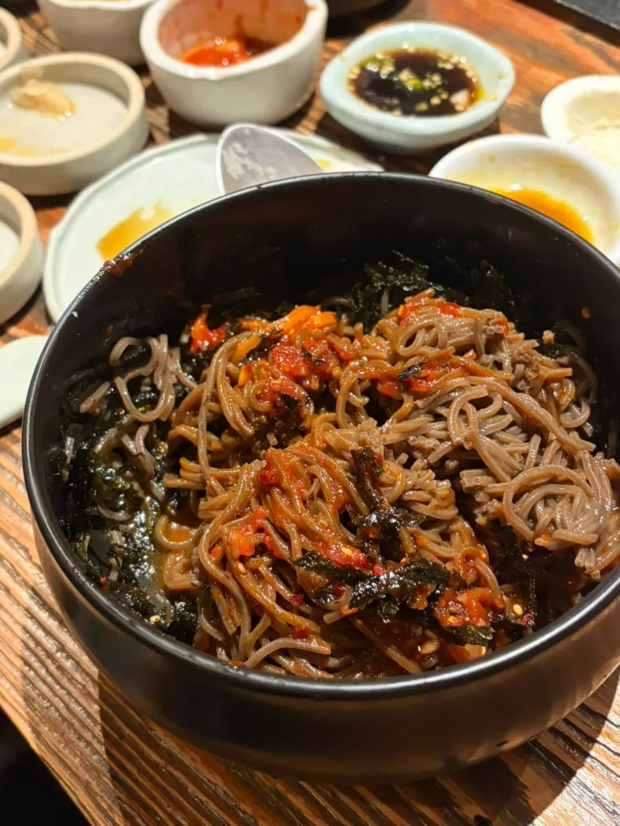 Fresh buckwheat bibim mak-guksu piled high with seaweed