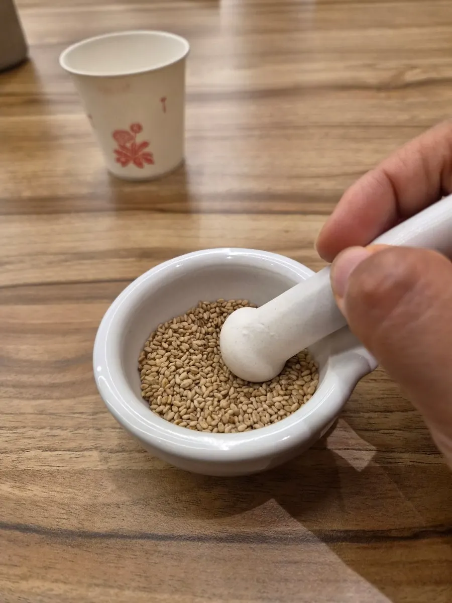 Whole sesame seeds and grinding pestle on the table