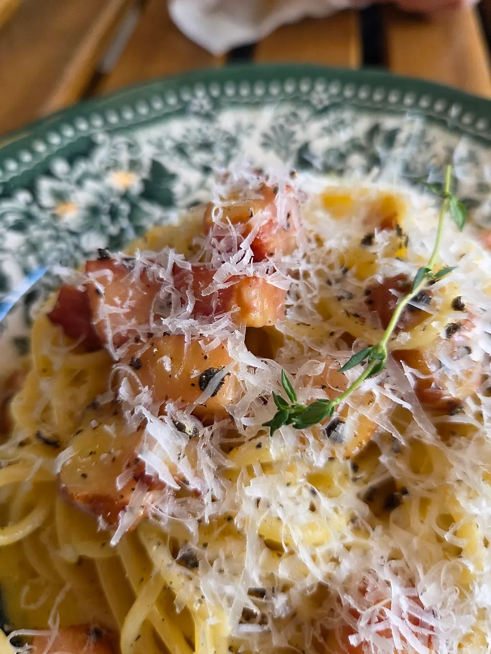 Carbonara topped with parmesan cheese and whole black pepper