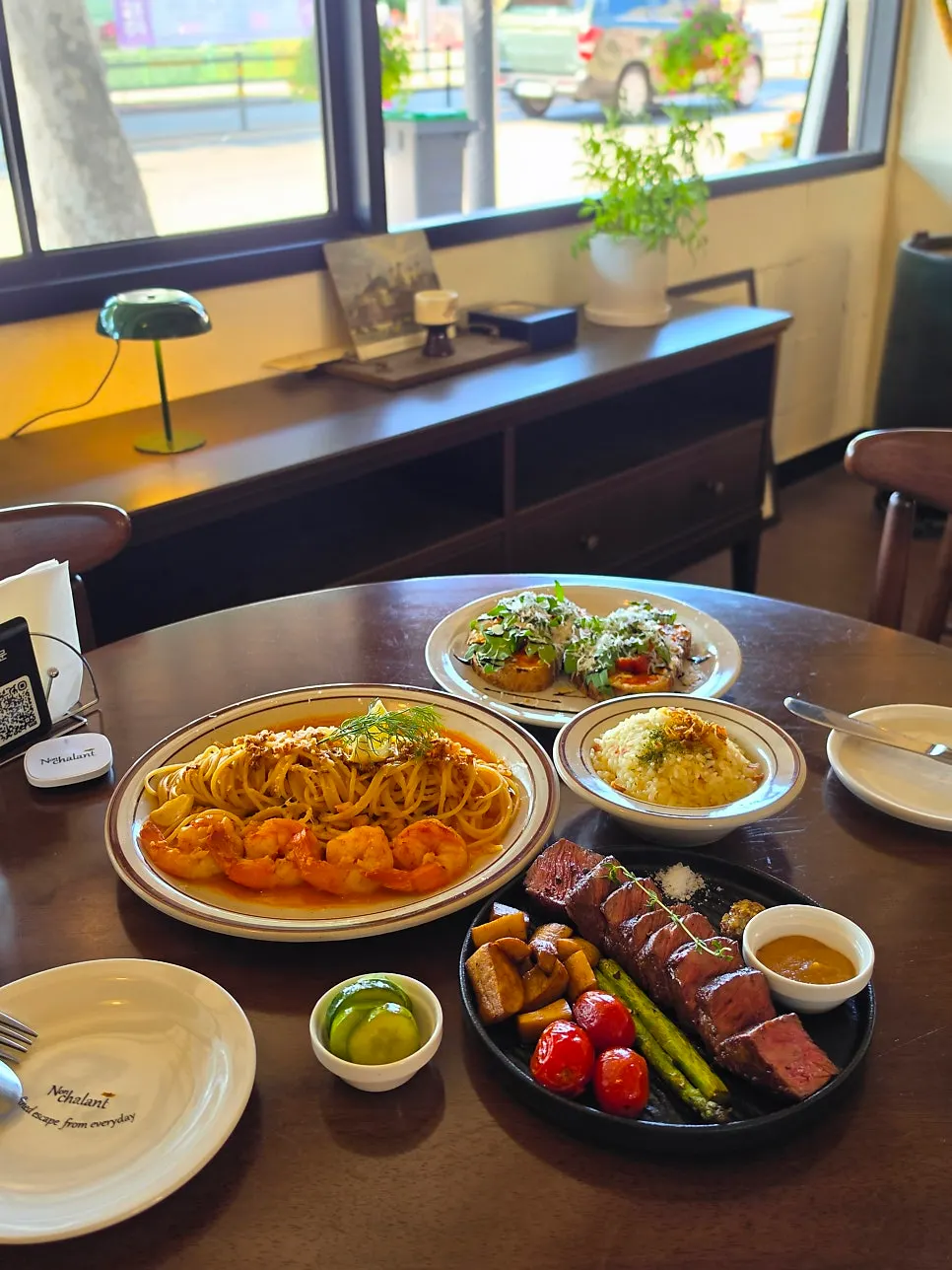 Table with steak platter and pasta at Nonchalant Lounge