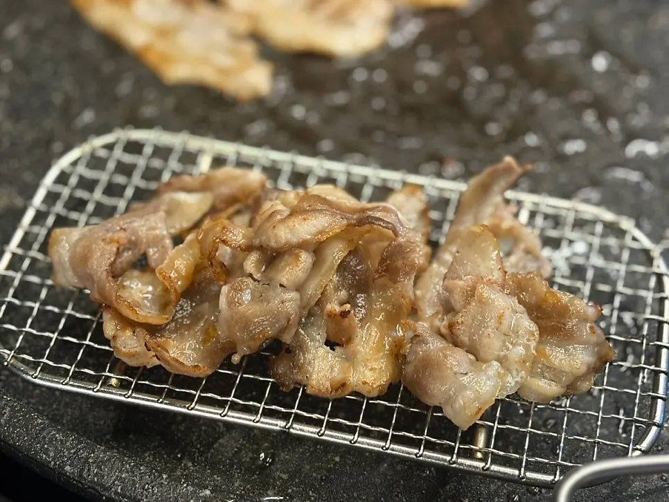 Thin-sliced pork belly spread out and grilled on the pan