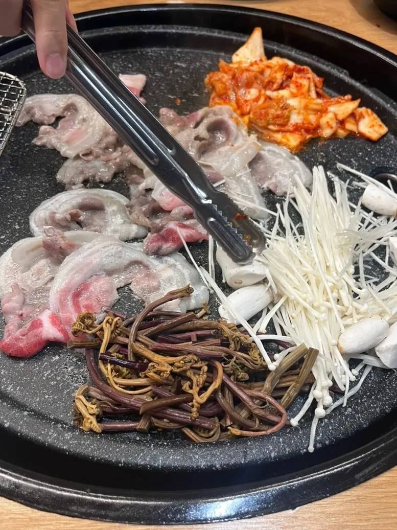 Thin-sliced pork shoulder cooking on the grill