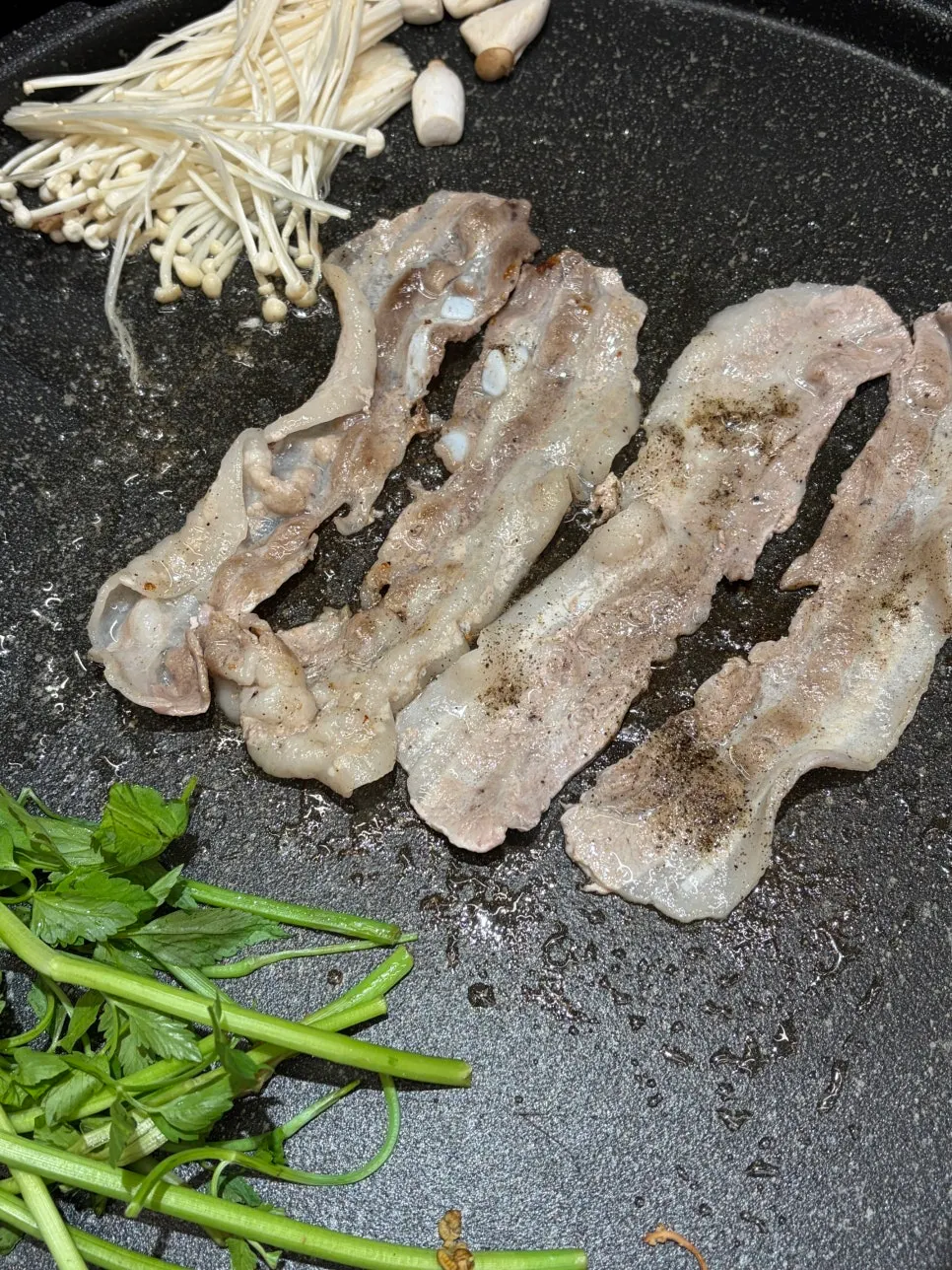 Thin-sliced pork belly grilling on the stone plate