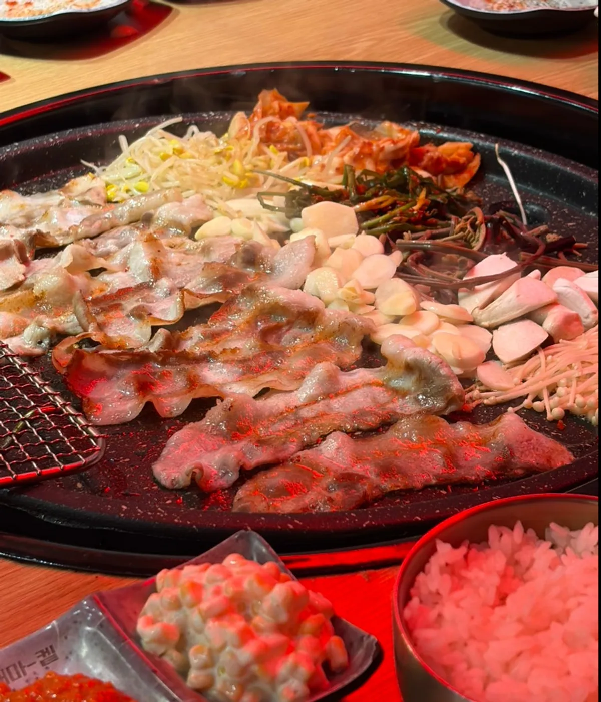 Thin-sliced pork belly and side ingredients on the grill