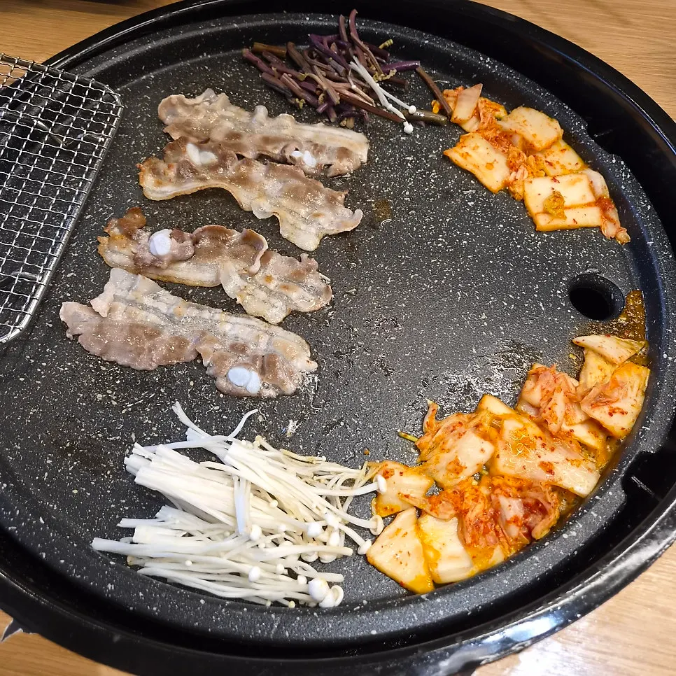 Thin-sliced pork belly cooking on a grill