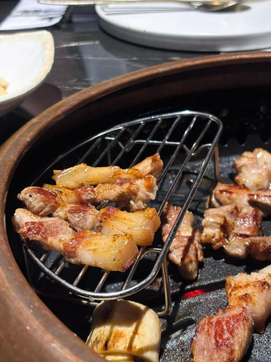 Black pork being cut into bite-sized pieces while grilling
