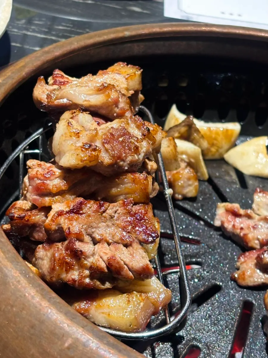 Staff member grilling black pork on the tabletop grill