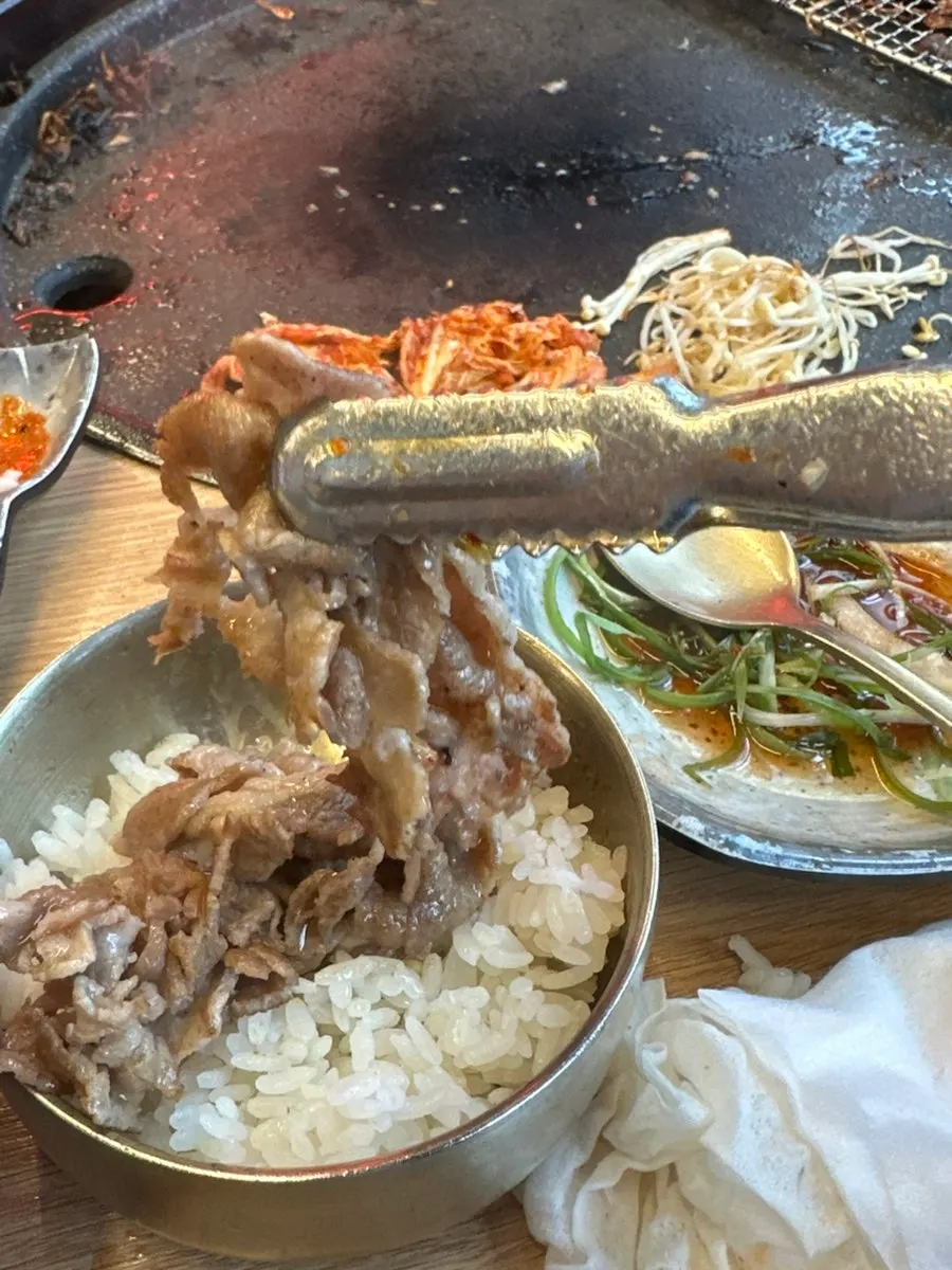 Thin-sliced pork neck falling apart in the tongs
