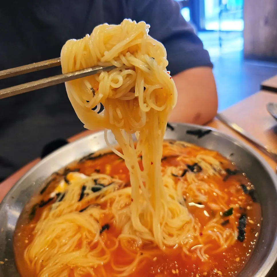 Lifting up the bouncy noodles from the kimchi noodle soup