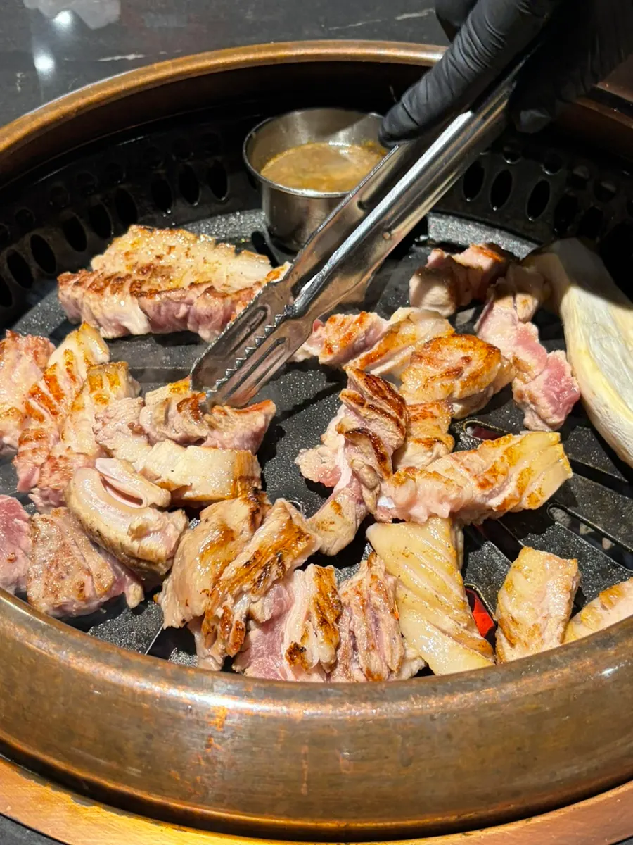 Staff member grilling the black pork over charcoal