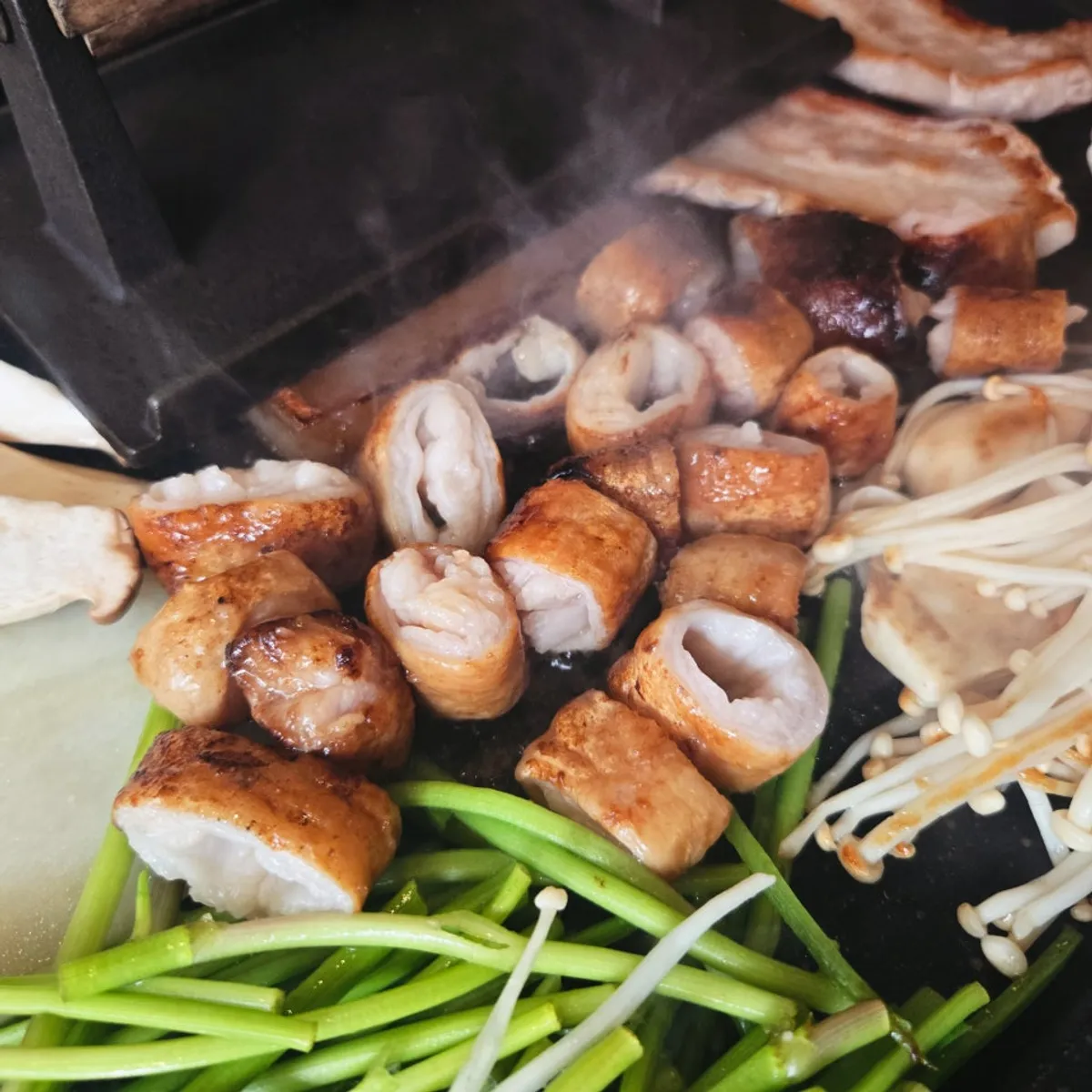 Pre-grilled raw makchang being cut with scissors while cooking