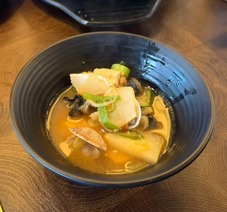 Broth scooped up showing mussel meat in the doenjang stew