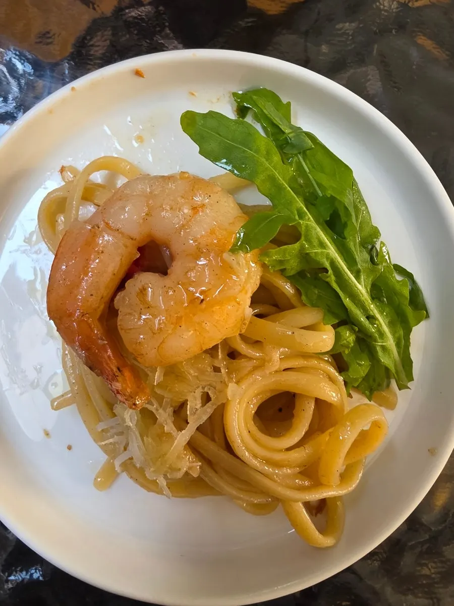 A bite of shrimp oil pasta with arugula and cheese