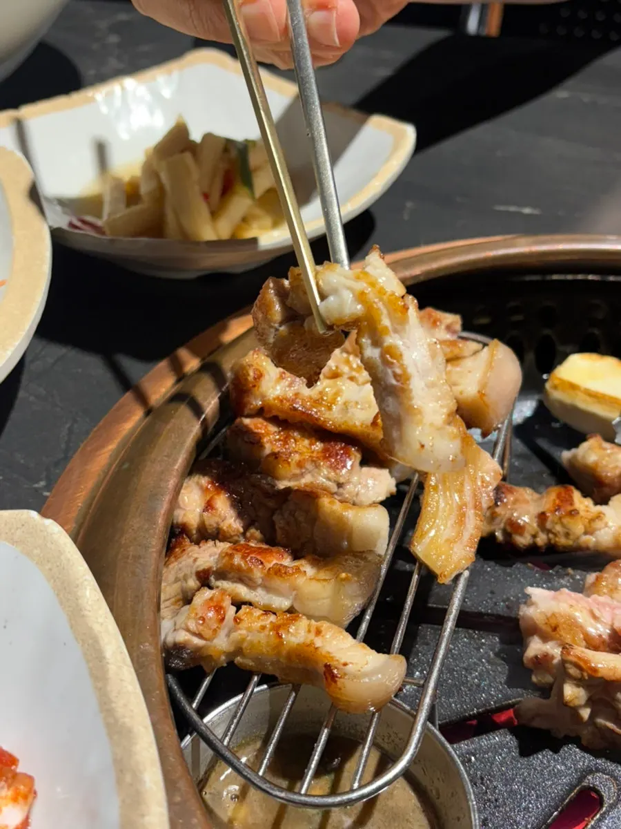 Bowl of myeoljeot beside grilled meat on the grill