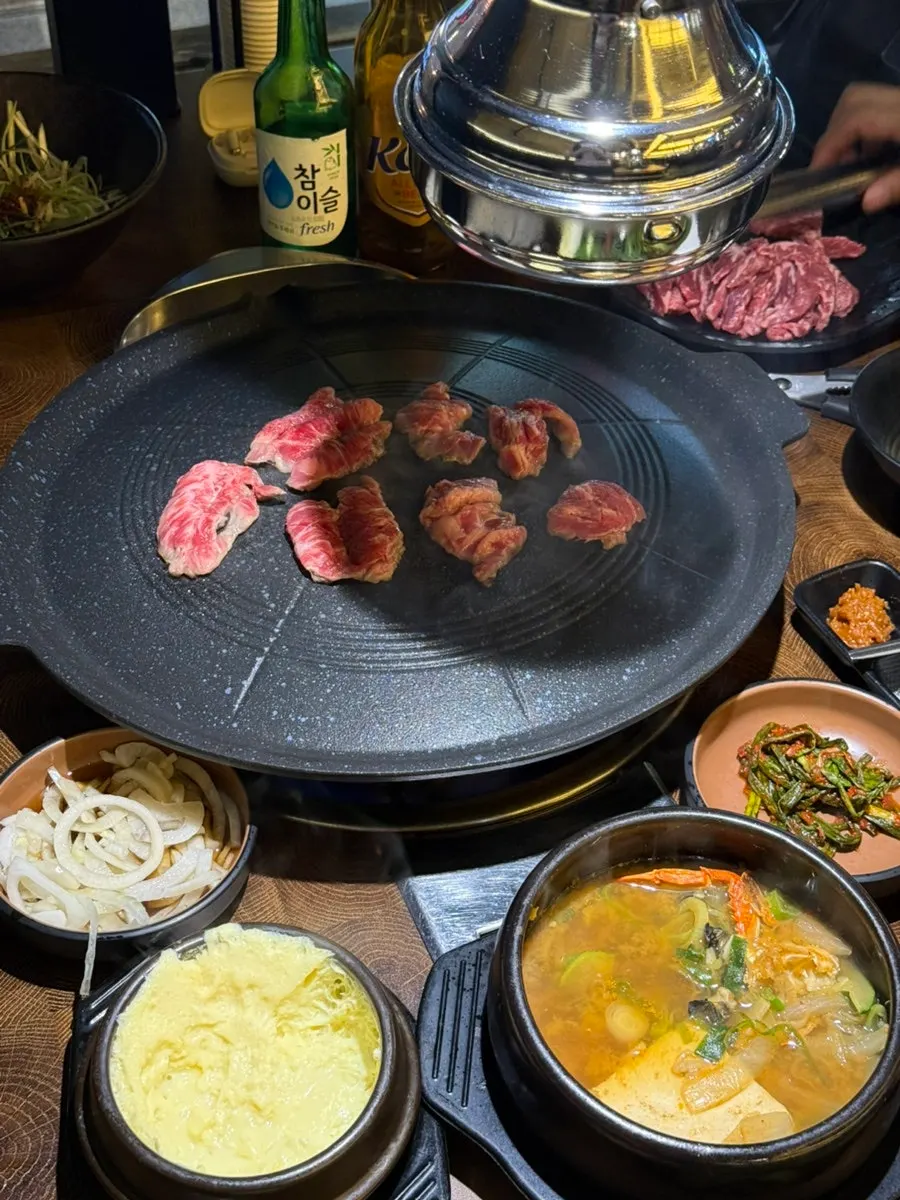 The hood lowered over the table while meat grills on the cauldron lid