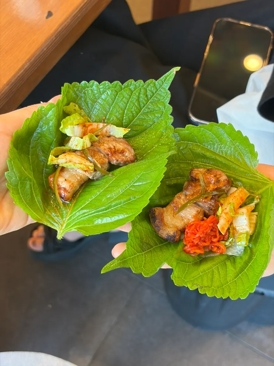 A wrap of black pork with radish salad and side dishes