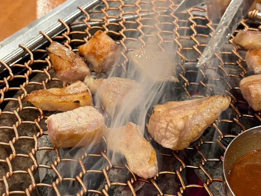 Thick-cut black pork browning golden on the grill