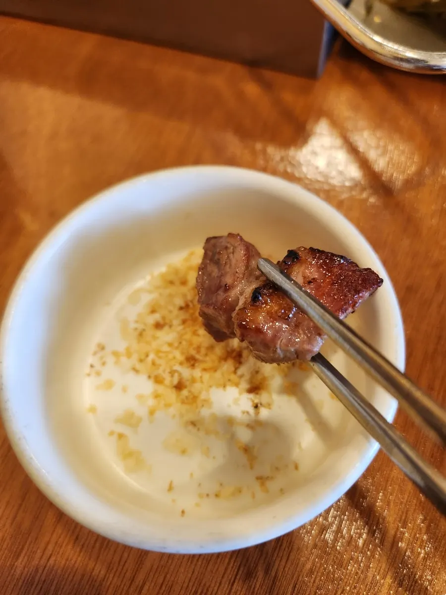 Pork belly grilling to a golden brown over charcoal