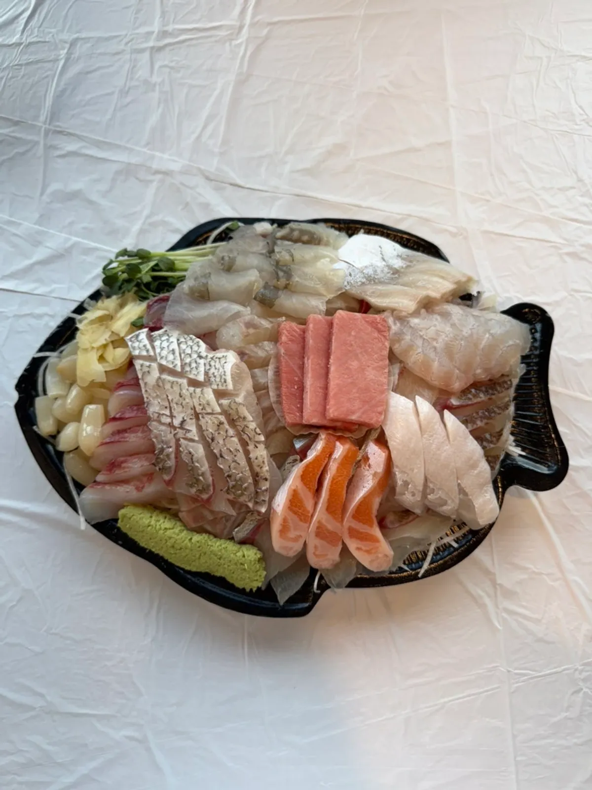 Plate of Ttangkkeut Maeul's 3-kind assorted sashimi with plastic wrap removed