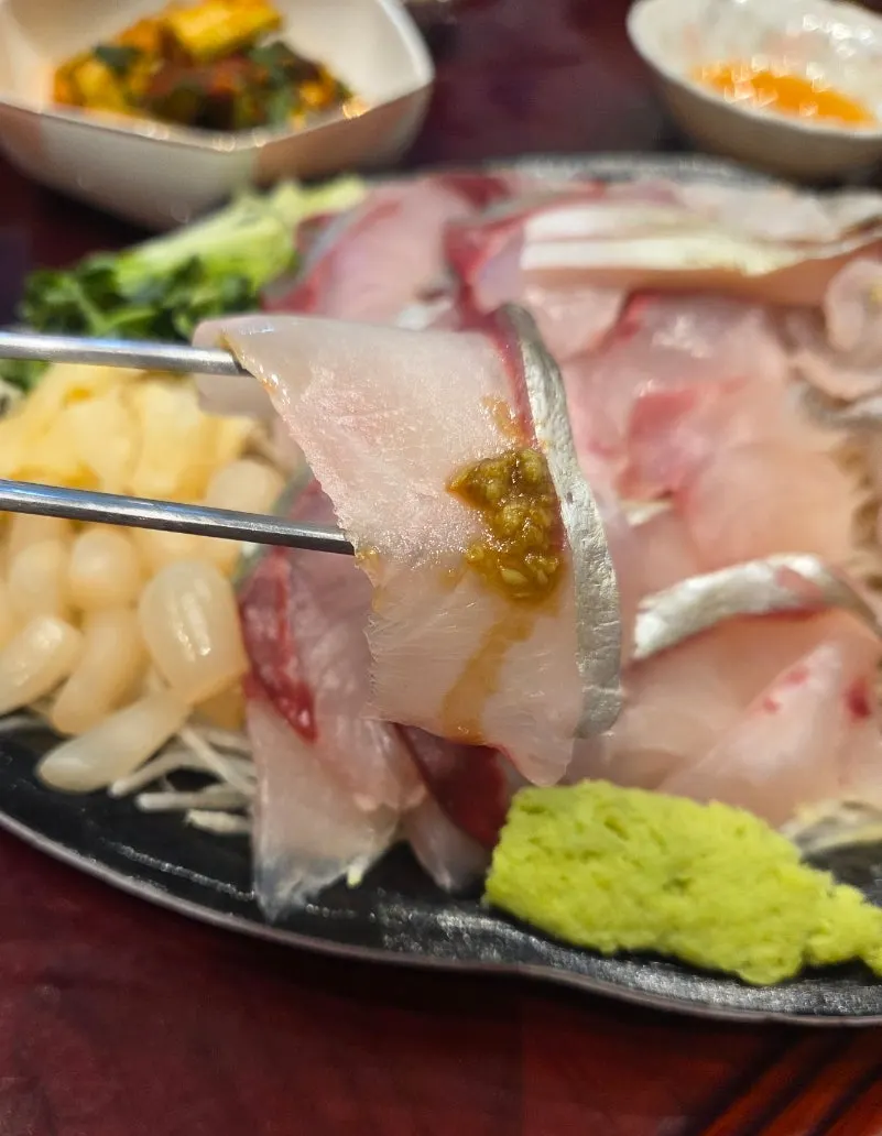 세꼬시 한 점을 집어 든 모습
