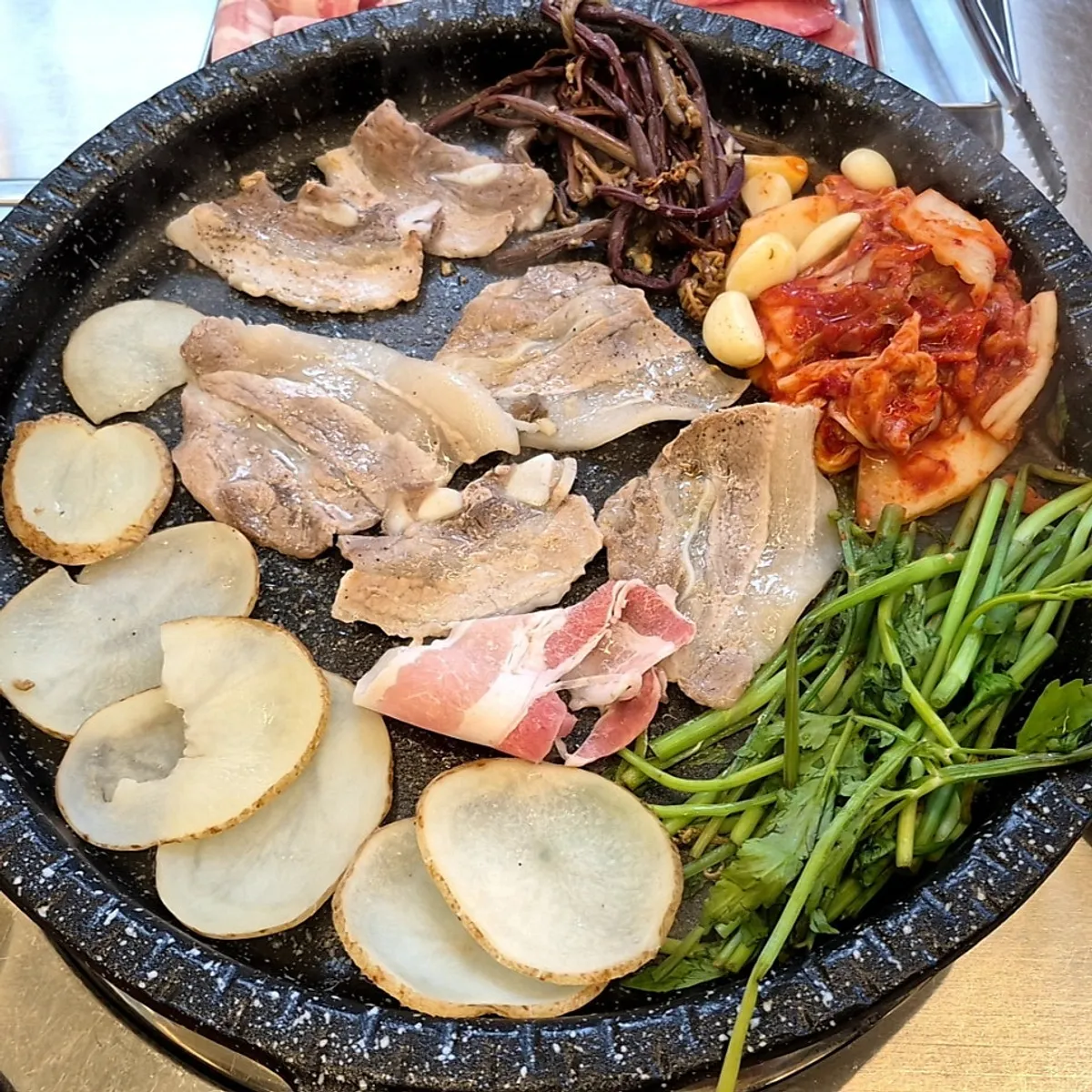 Grill pan piled with frozen pork belly and vegetables