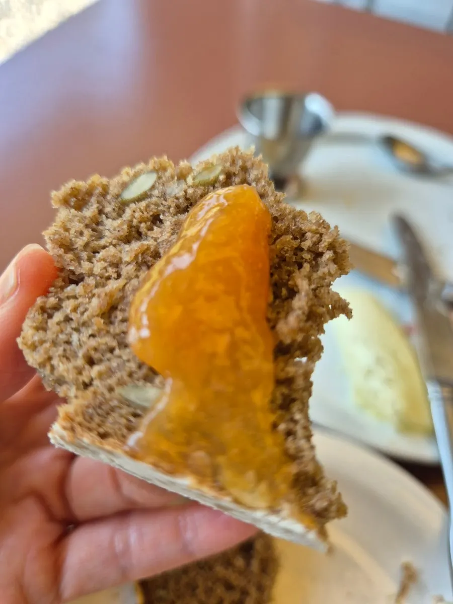 A bite of wheat bread topped with house-made jam and hazelnut butter