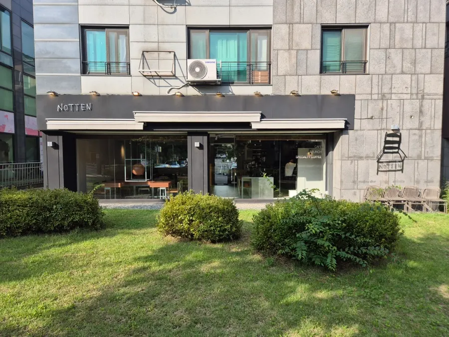 카페 앞 잔디와 나무가 있는 작은 정원
