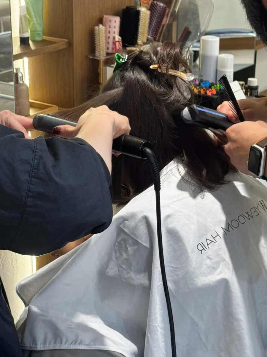 Finishing the straight perm by flat-ironing the child's hair