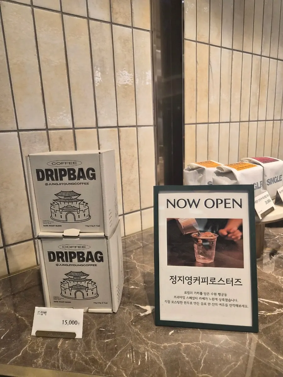 Coffee cup and sleeve held up in front of the department store escalators