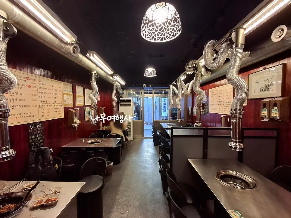 Interior of Moksam Hwaro with 4-person tables equipped with grills