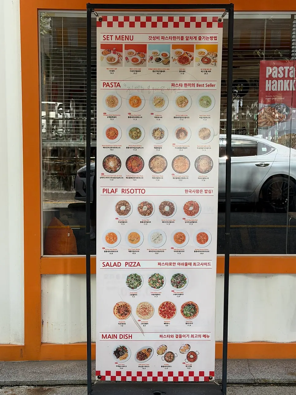Pasta Han Kki's menu board hanging outside the store