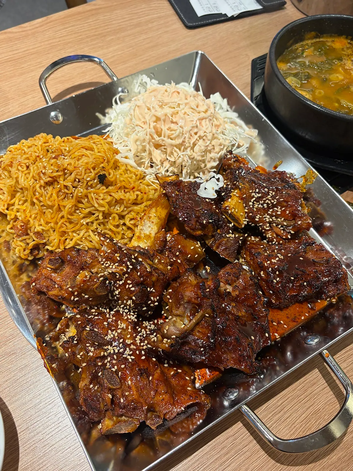 Hot plate of grilled beef bones topped with ramyeon noodles