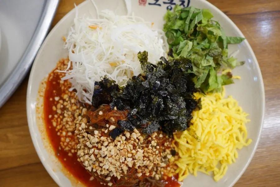 Jaengban makguksu topped with colorful garnishes