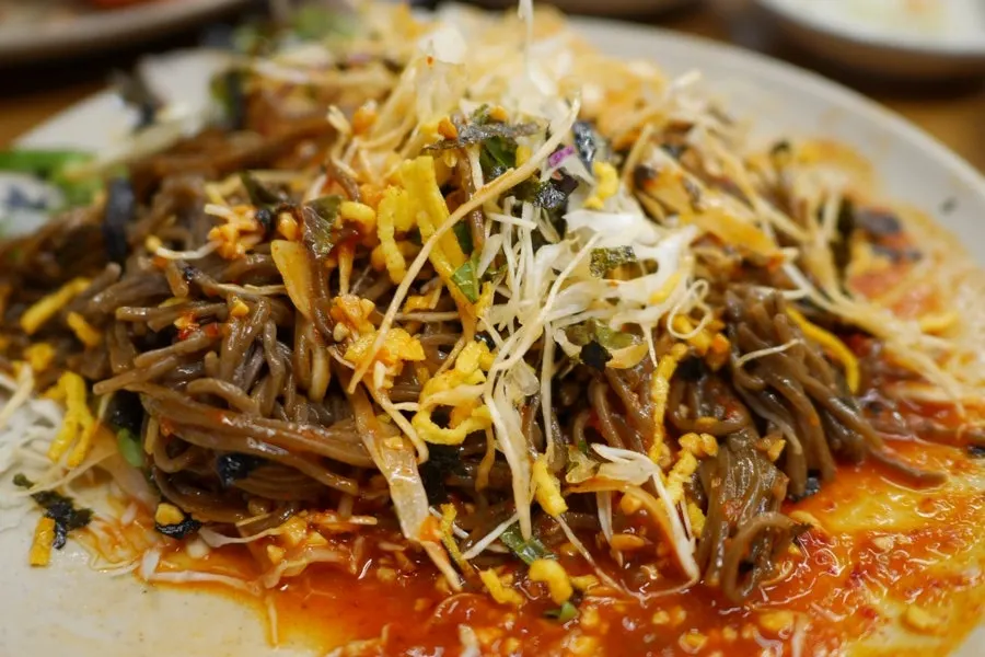 Jaengban makguksu mixed with sauce and vegetables