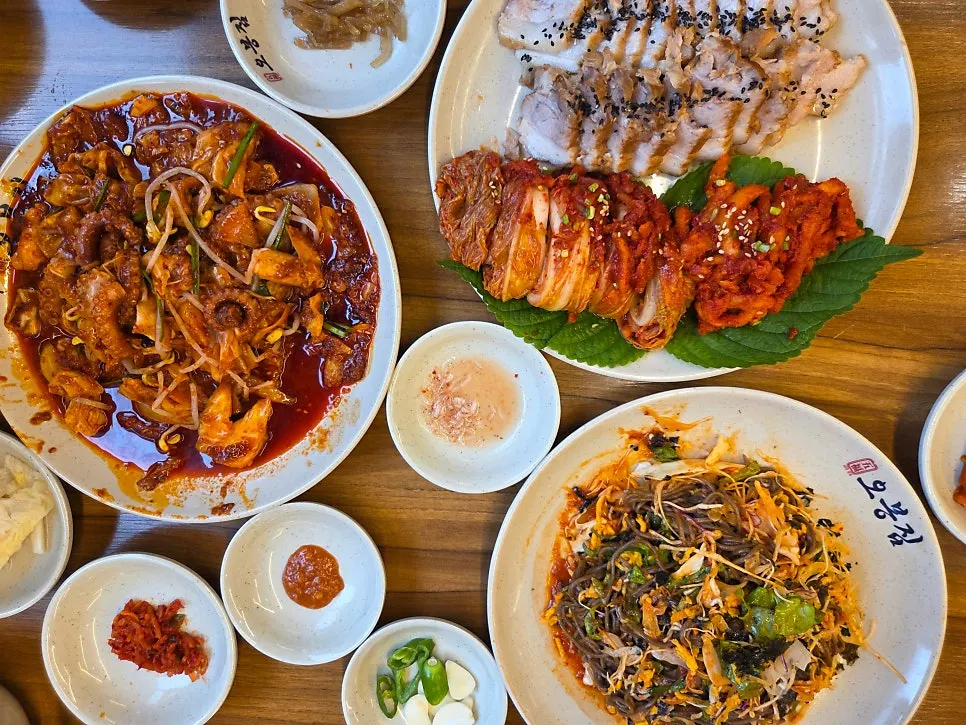 Table set for four with octopus stir-fry, bossam, and jaengban makguksu