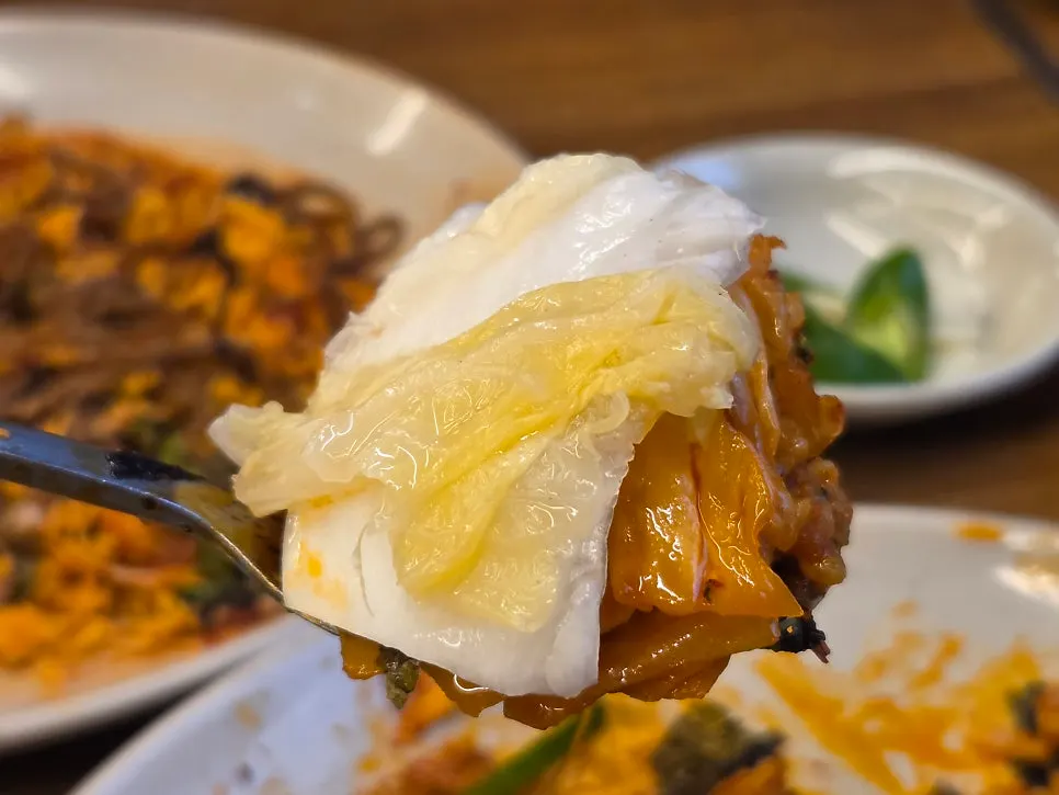 A bite of octopus stir-fry topped with white kimchi