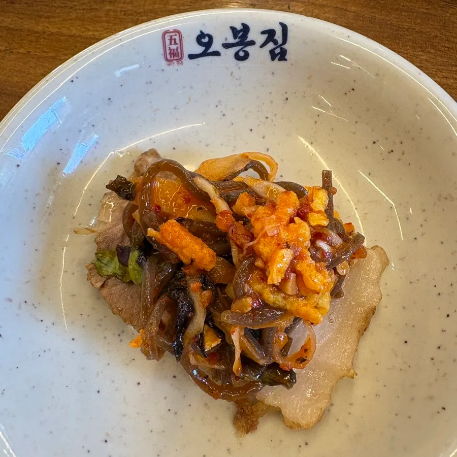 A piece of bossam topped with radish kimchi