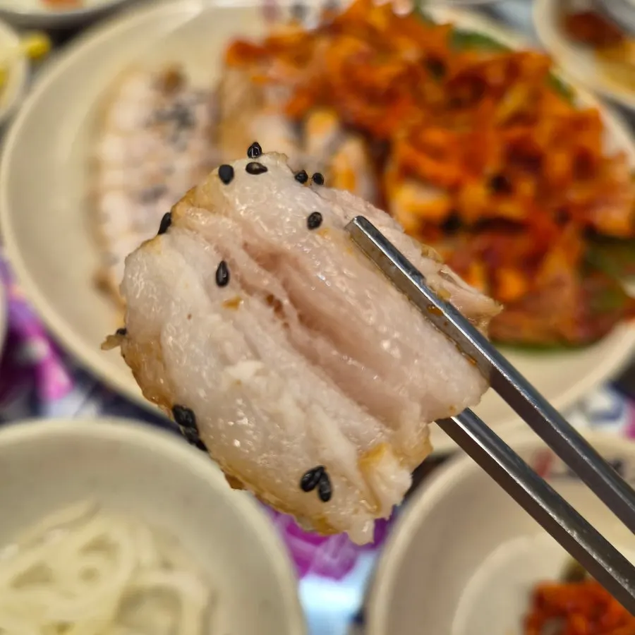 A bossam wrap topped with kimchi and pickled radish