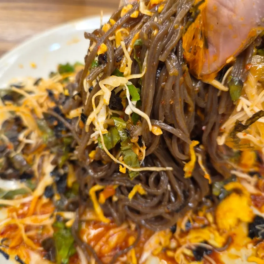A chopstick-full of mixed makguksu noodles