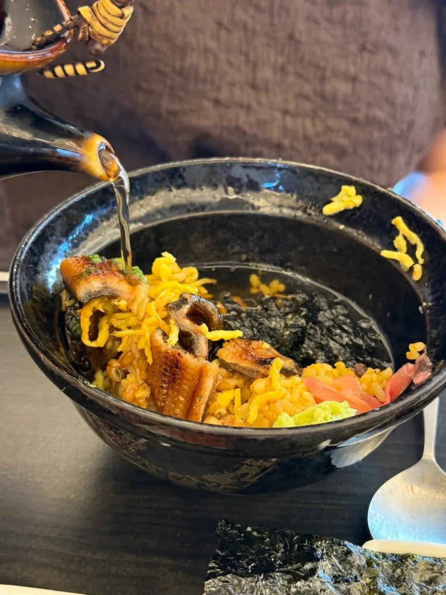 A spoonful of eel and rice topped with wasabi