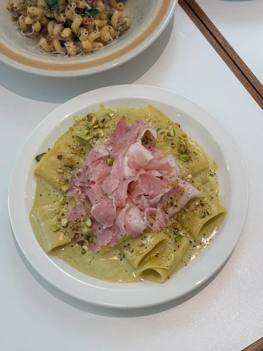 A bowl of pistachio pasta served with jambon