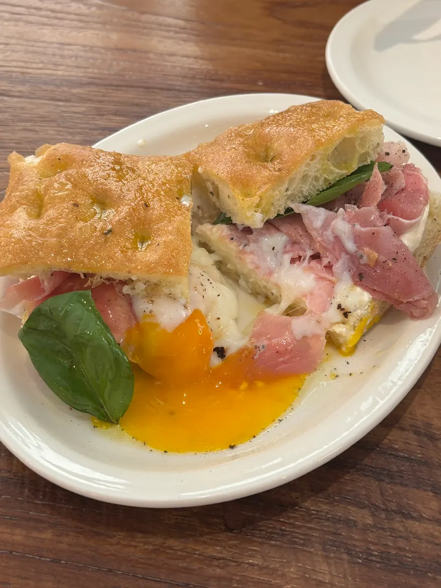 Focaccia sandwich with the poached egg yolk broken open