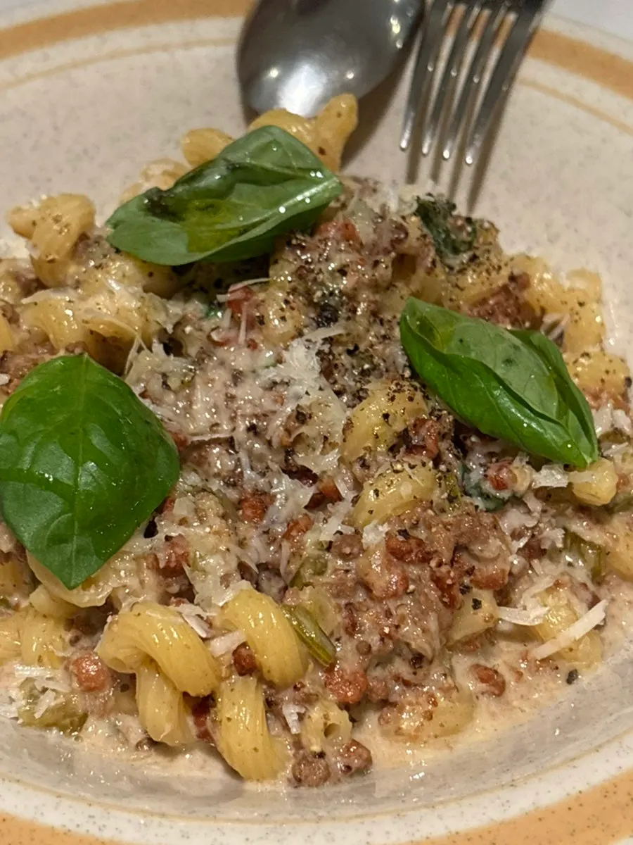 A plate of pasta topped with white ragù sauce