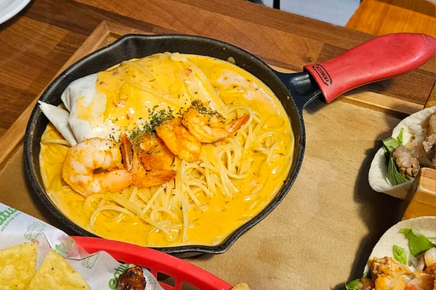 Chipotle cream pasta topped with three whole shrimp